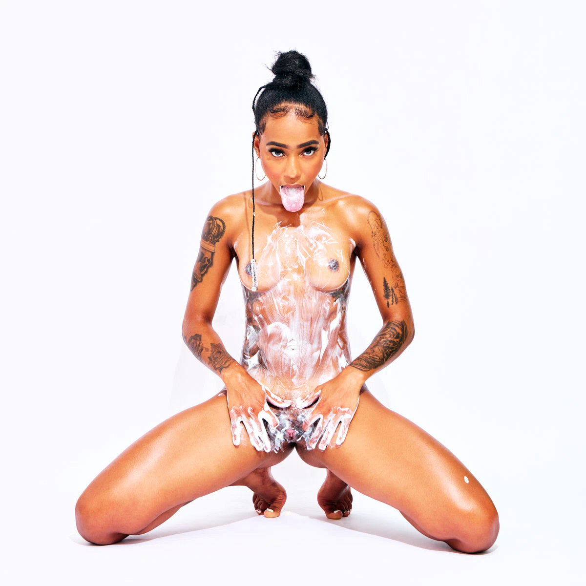 Tattooed Cape Verdean model African Beauty nude applying cream on her body