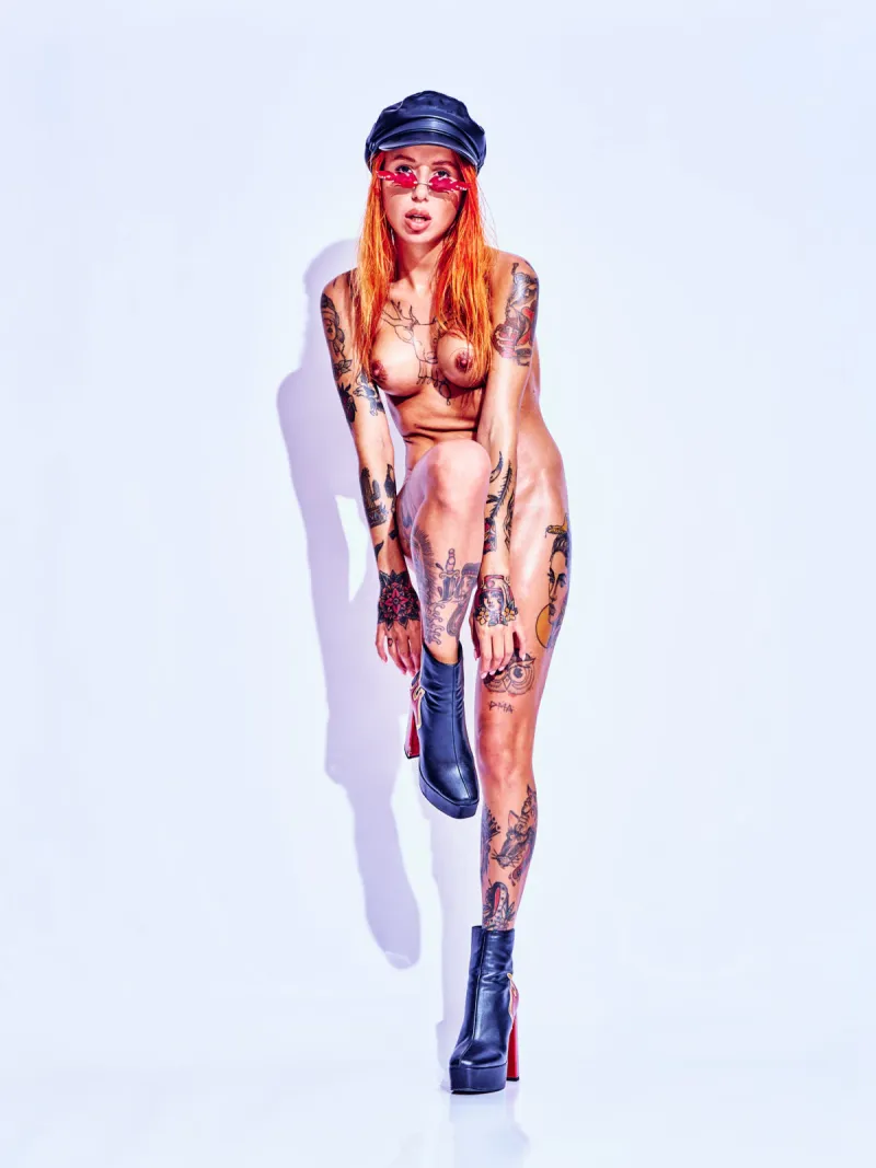 Nude art portrait highlighting Ana Almeida’s tattoos with flame-themed accessories.