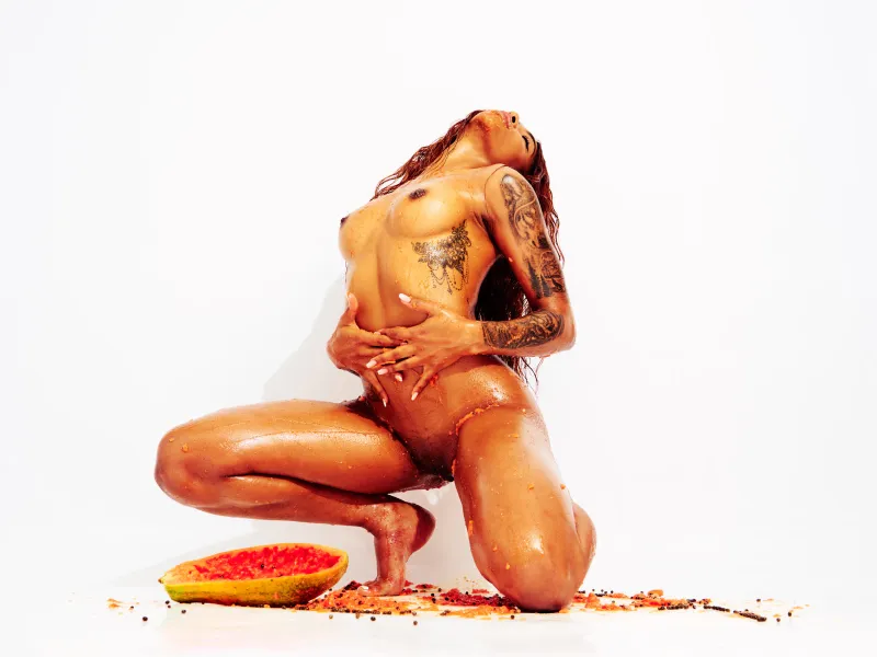 African Beauty nude with tattoos, covered in papaya in a sensual art photography series.