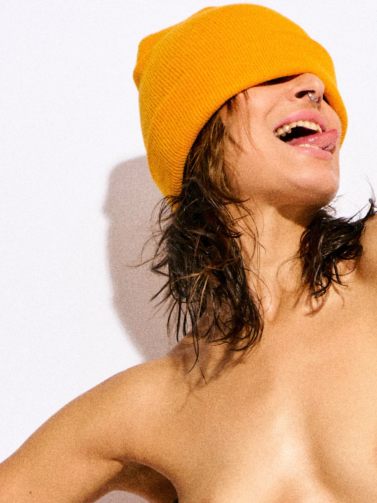 Tall nude art model Reb Chi wearing a bright yellow beanie in minimalist photography.