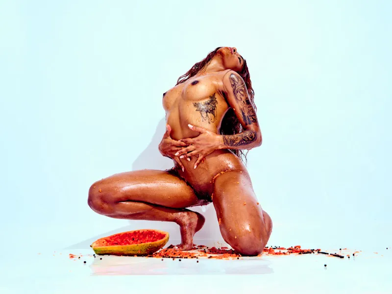 African Beauty nude with tattoos, covered in papaya in a sensual art photography series.
