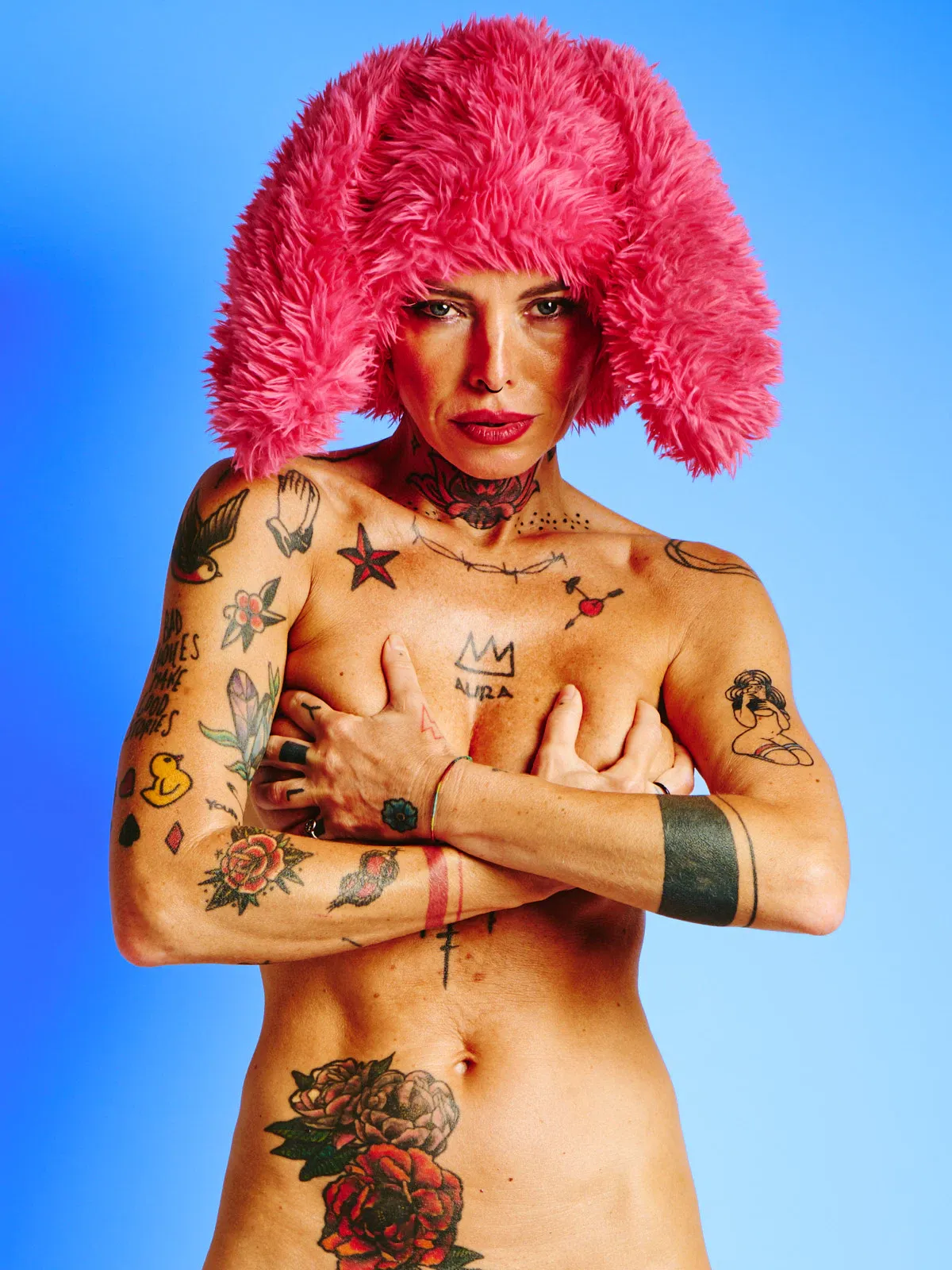 Tattooed nude model in the Red Rabbit series wearing red fur hat with rabbit ears