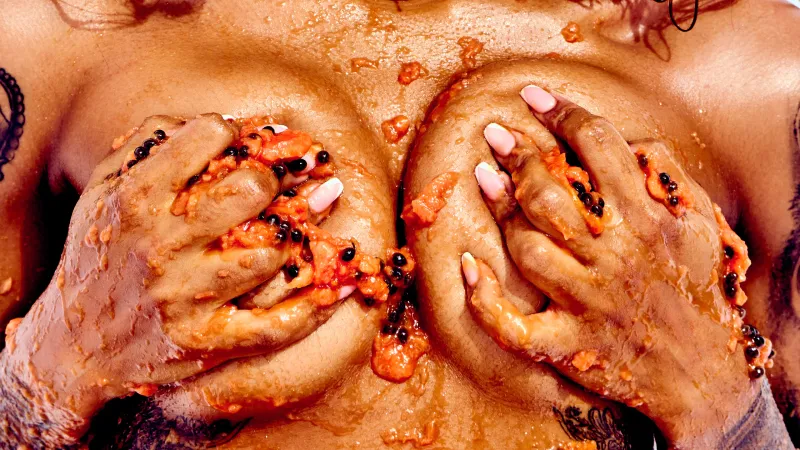 African Beauty nude with tattoos, covered in papaya in a sensual art photography series.