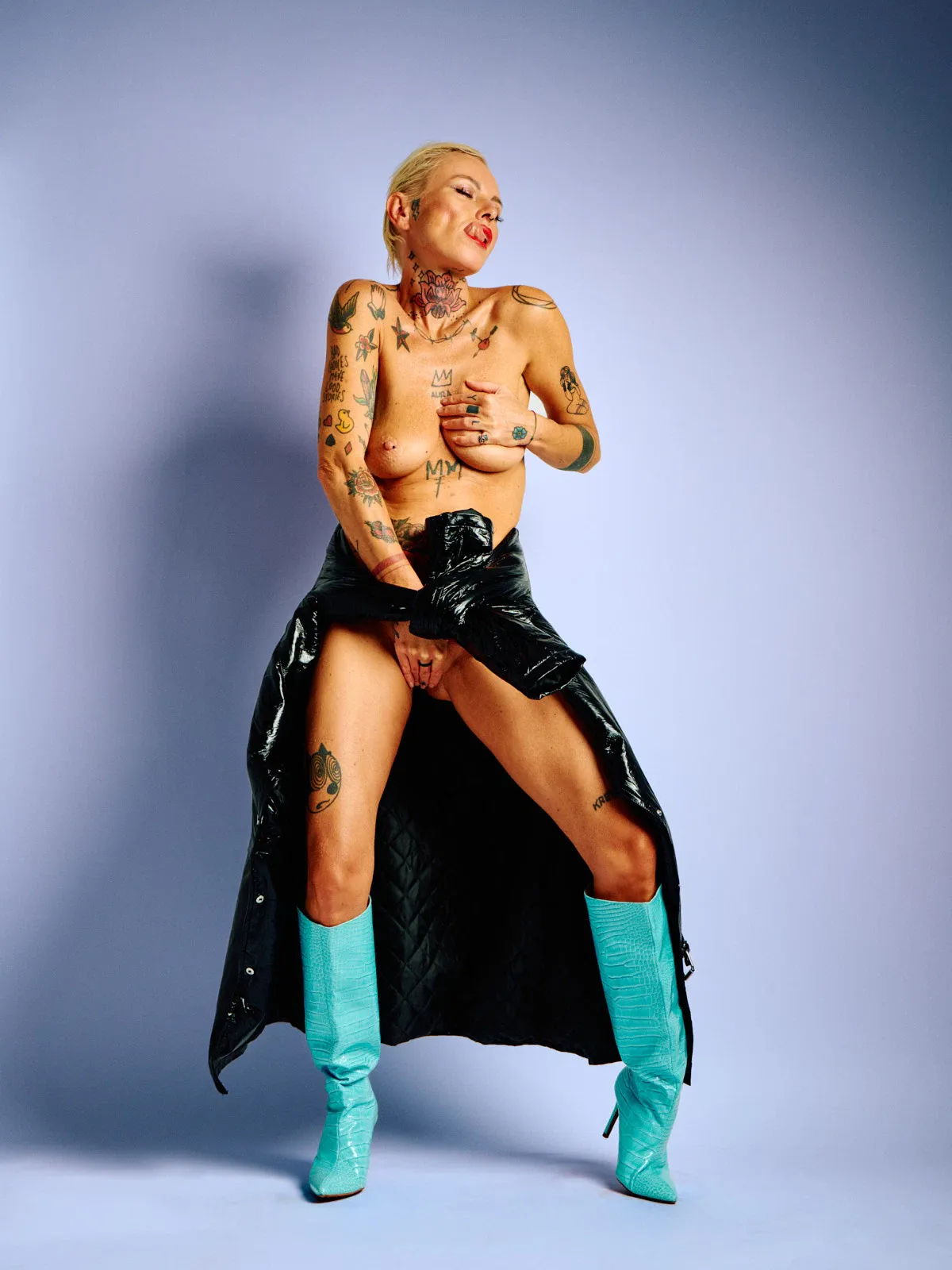 Lu Epic nude in a black latex coat and blue boots, posed in a minimalist art portrait