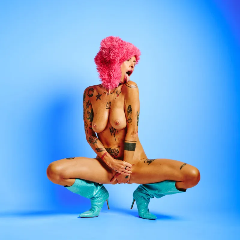 Tattooed nude model in the Red Rabbit series wearing red fur hat with rabbit ears