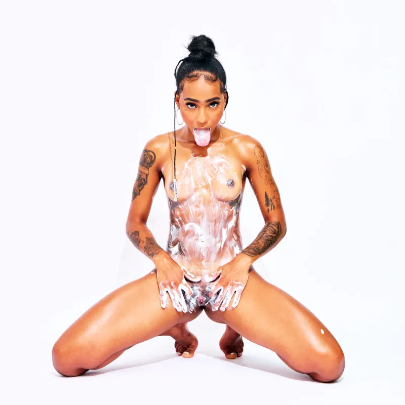 Tattooed Cape Verdean model African Beauty nude applying cream on her body